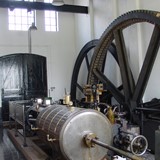 Tandwielen en stoomketel in het ketelhuis van stoomgemaal 'Hertog Reijnout.' © Gelders Archief (4190-6353), PD.