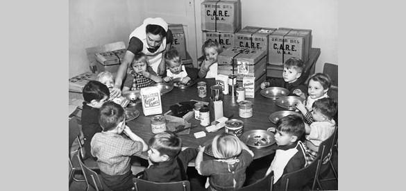 Een verpleegster voedt Nederlandse kinderen uit CARE-pakketten, circa 1953.
