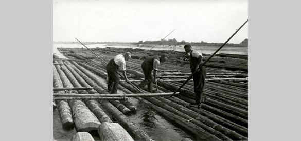 Tot 1968 vond er nog houttransport plaats op de Rijn. Op deze foto uit 1933 is te zien hoe arbeiders de stammen bijeen houden. Het hout kwam uit Duitsland. Eindbestemming was de houthaven van Zaandam.