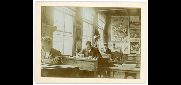 Ontwerpers aan het werk in de tekenkamer, met aan de muur veel oude ontwerpen. Arnhemsche Steendrukkerij en Etikettenfabriek, periode 1900-1940.
