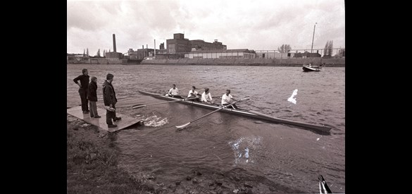 Tewaterlating van een roeiboot met op de achtergrond de ENKA fabriek, 1982.