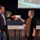 Voorzitter Dittie van Zee (rechts) overhandigt het eerste exemplaar aan wethouder Van Stappershoef (links) © Den Ouden Dijk
