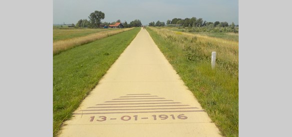 De locaties van de twee dijkdoorbraken van 1916 zijn met een markering in het fietspad aangegeven.