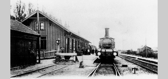 Het houten stationsgebouw met een stoomlocomotief omstreeks 1900.