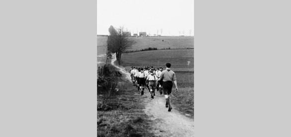 Een verkennersgroep loopt over de Zevenheuvelenweg richting Derdebaan. Het is 4 mei 1947, de dag van de opening van de Canadese Erebegraafplaats.