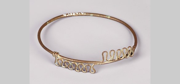 Deze Romeinse armband van bronsdraad is gevonden tussen Rossum en Tiel. De armband kan op ingenieuze wijze vernauwd of verwijd worden. Hij werd over de bovenarm gedragen.