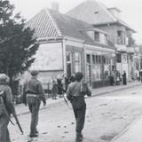 Canadese soldaten lopen over de Hogestraat in Dieren naar het politiebureau, waar ze contact maken met de Britten van het Hallamshire Bataljon. De Duitse troepen in West-Nederland zijn afgesneden.