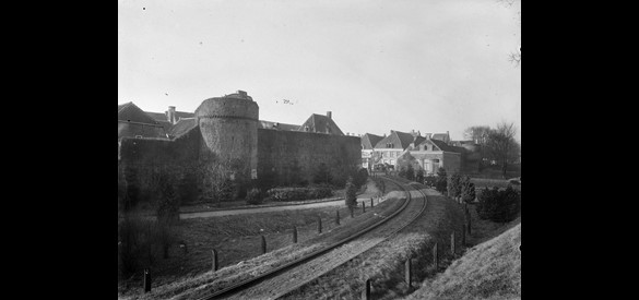 Elburg: zicht op gedeelte van de stadsmuur met halfronde muurtoren en spoorlijntje