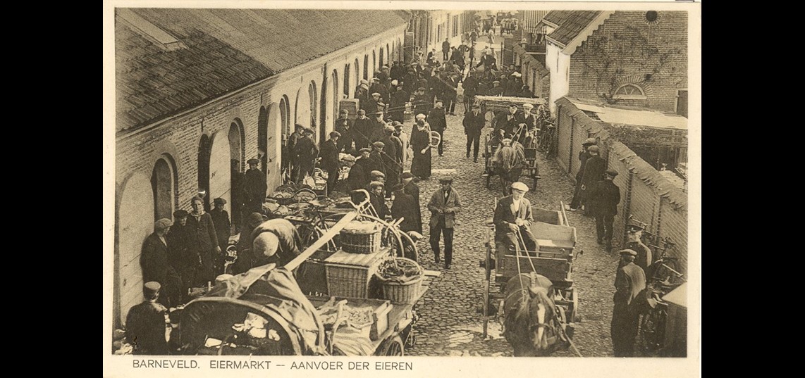 “Barneveld. Eiermarkt -  Aanvoer der eieren”. Links de in 1913 gebouwde eerste eierhal aan de Langstraat. Bron: Gemeentearchief Barneveld
